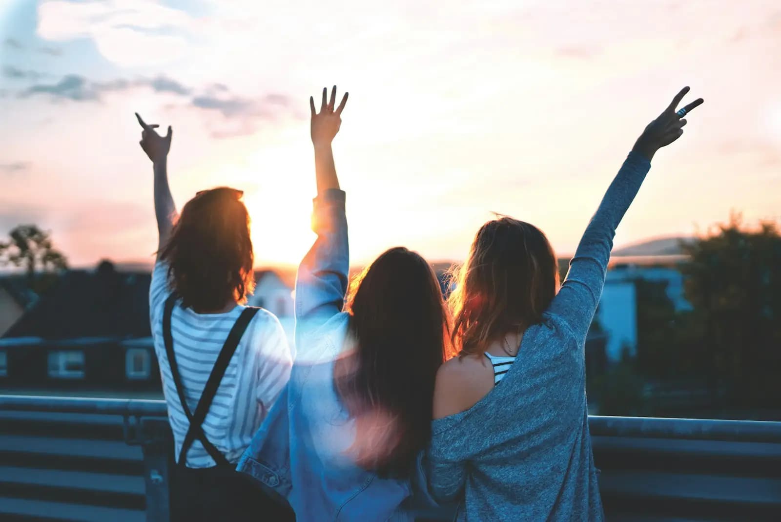 Tri osobe podignutih ruku u zalazak sunca
